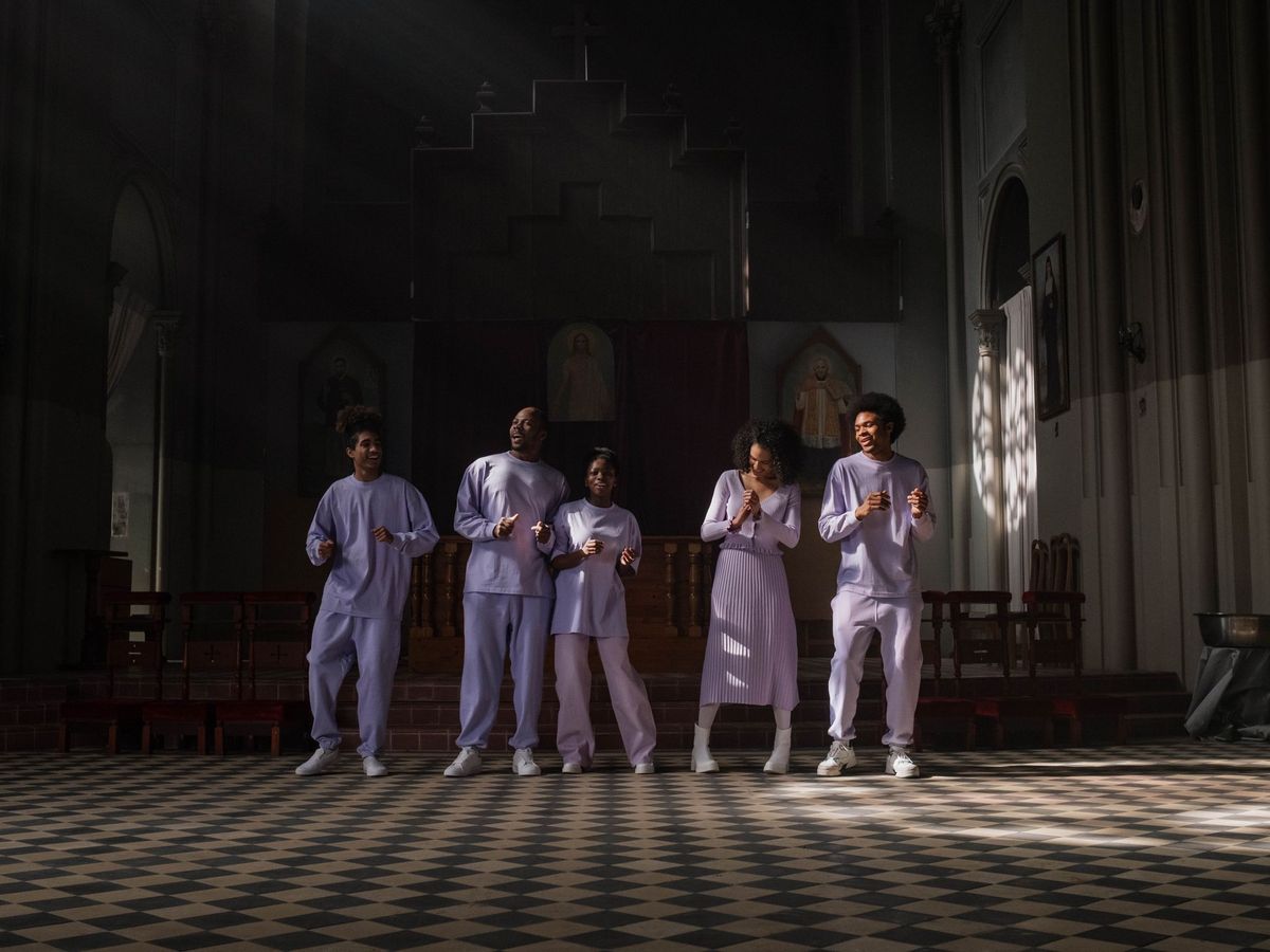 A choir practising together, lit by rays of sunlight through a church window